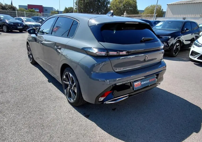Vue 3/4 arrière d'une Peugeot 308 Hybrid gris métallisé avec jantes alliage 17 pouces, stationnée en extérieur.
