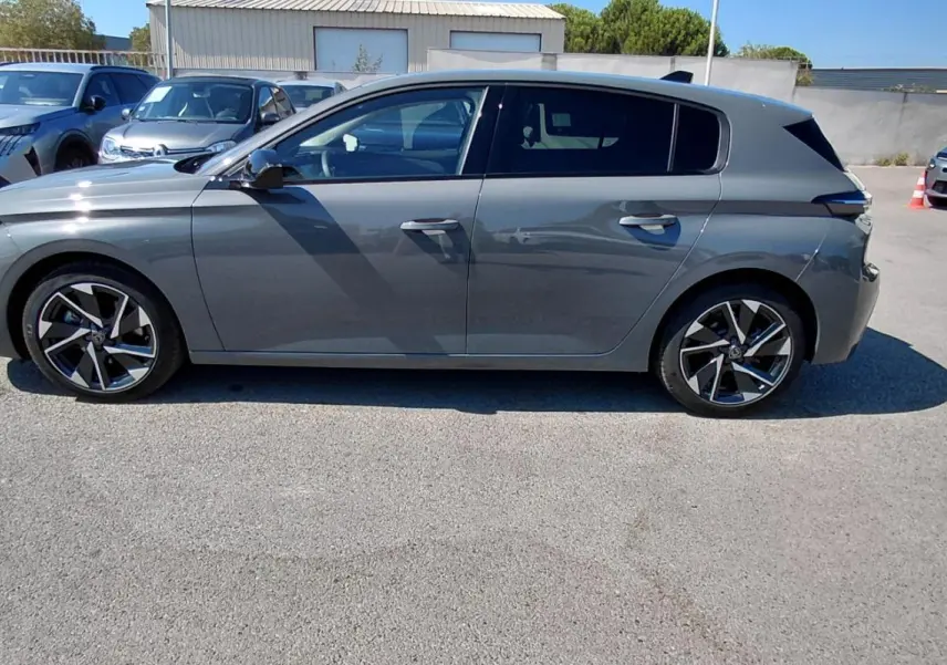 Profil côté gauche d'une Peugeot 308 gris métallisé avec jantes alliage 17 pouces, en extérieur sur parking.