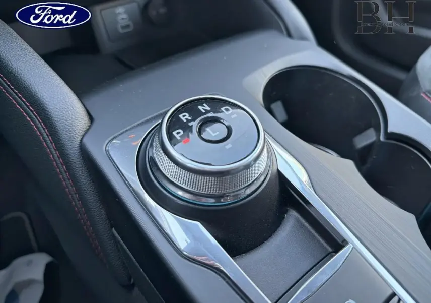 Gros plan sur la molette de boîte automatique du Ford Kuga 2023, avec console noire et surpiqûres rouges visibles.