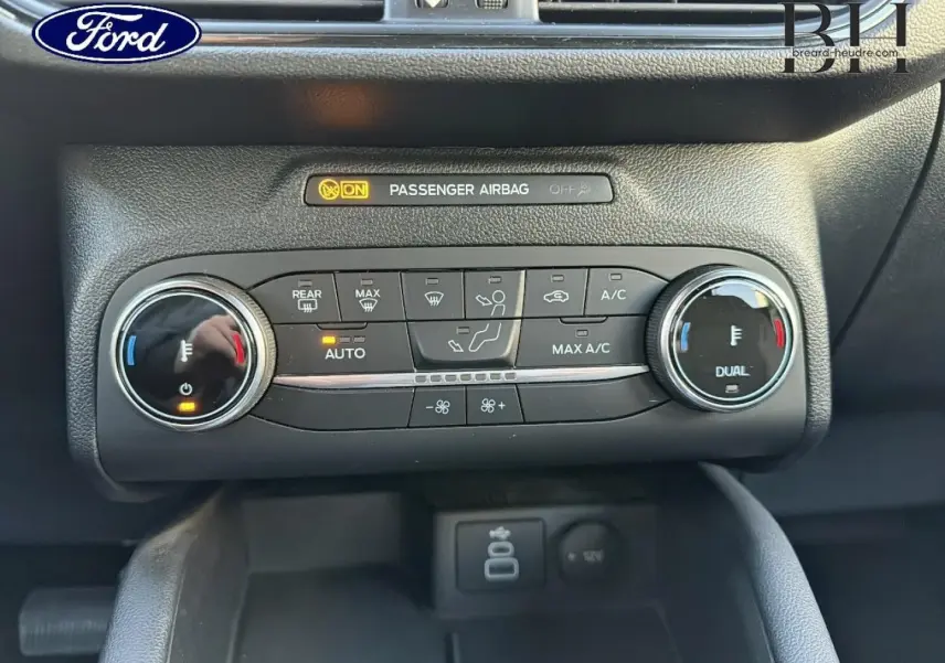 Gros plan sur la console centrale du Ford Kuga 2023, montrant les commandes de climatisation bi-zone et les voyants actifs.