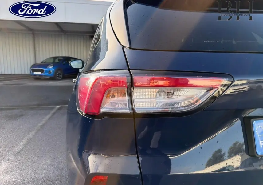 Vue arrière droite du Ford Kuga bleu avec feux arrière LED et becquet distinctif visible.