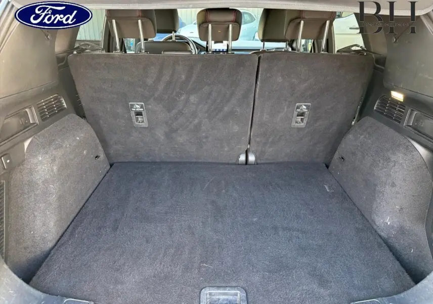 Coffre ouvert vu de l'arrière d'un Ford Kuga bleu, banquette arrière en tissu noir relevée.