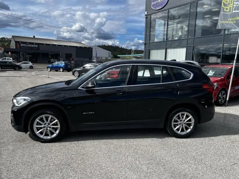Profil côté gauche d’un BMW X1 noir métal 2017, avec jantes alliage et vitres légèrement teintées, stationné en extérieur.