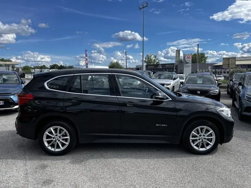 Profil côté gauche d'un BMW X1 20D noir métal 2017, avec jantes alliage et lignes épurées visibles en extérieur.
