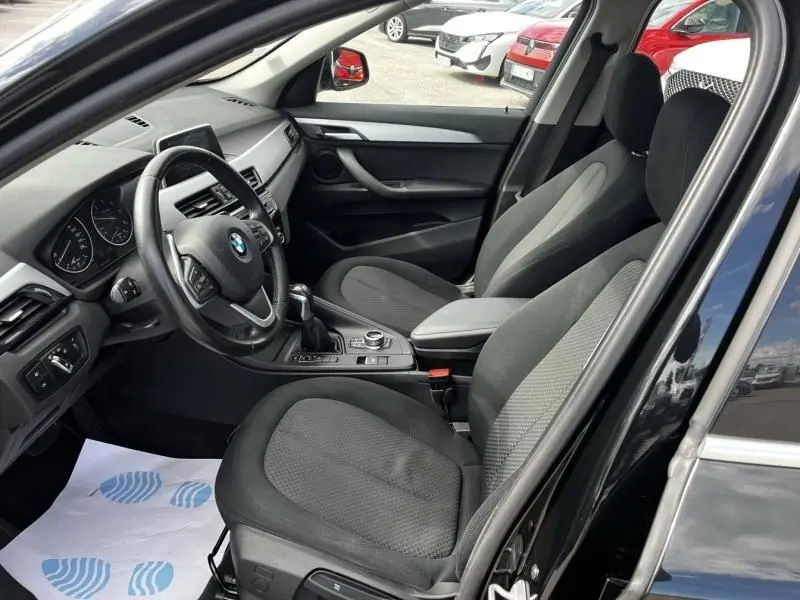 Intérieur noir du BMW X1 20D 2017, vue côté conducteur avec tableau de bord et sièges en tissu.