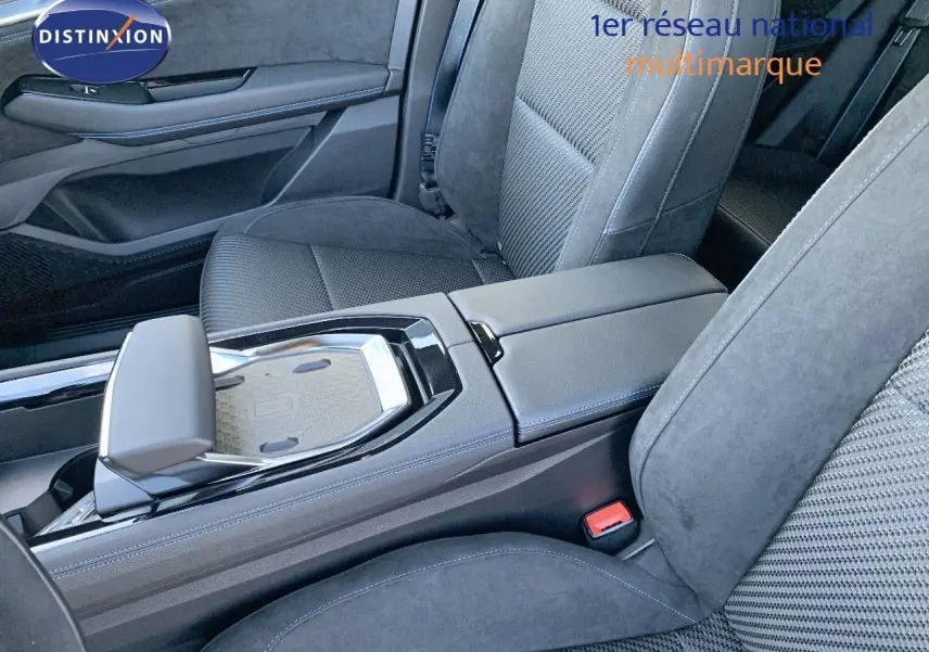 Vue intérieure centrée sur la console centrale et sièges avant en tissu noir du Renault Austral 2024 hybride.