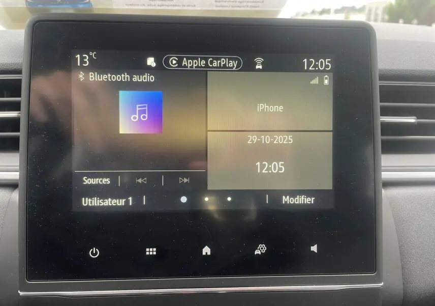 Écran tactile central du tableau de bord d'un Renault Captur bleu métal, affichant Apple CarPlay et Bluetooth audio.