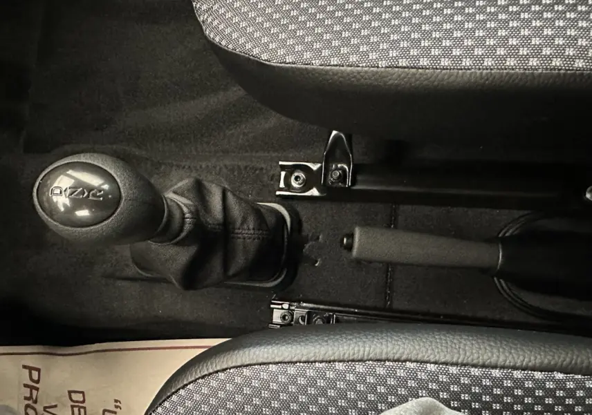 Le levier de vitesse et le frein à main au centre de l'habitacle d'une Aixam Ambition E City Pack rouge 2025.