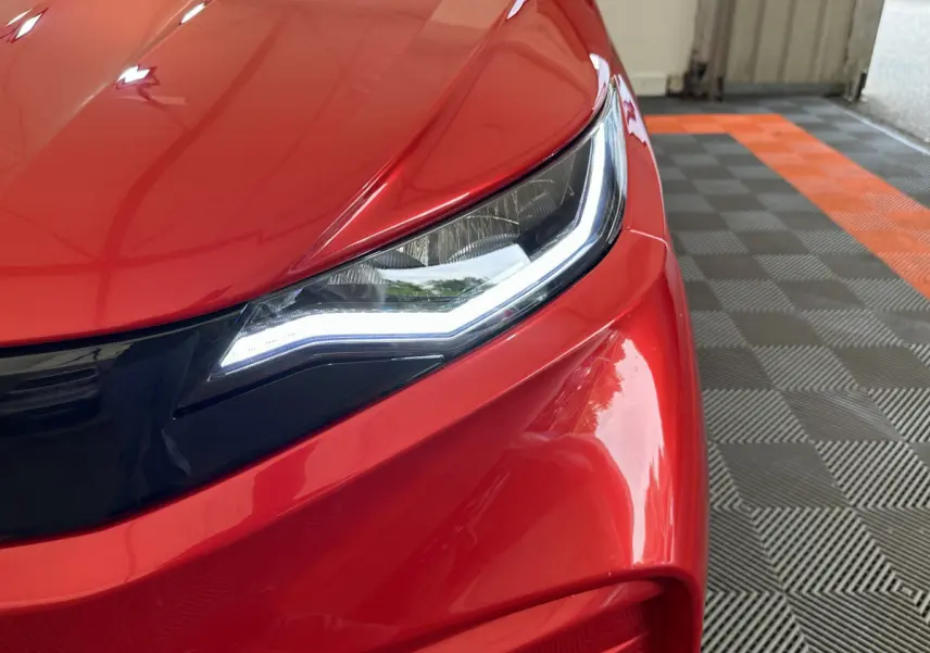 Gros plan sur le phare avant gauche d'une Aixam Ambition E City Pack rouge 2025 avec éclairage LED distinctif.