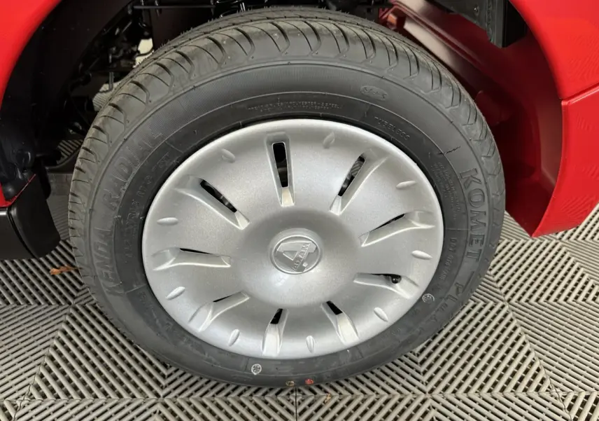 Gros plan sur la roue avant gauche d'une Aixam Ambition E City Pack rouge avec enjoliveur argenté au design aéré.
