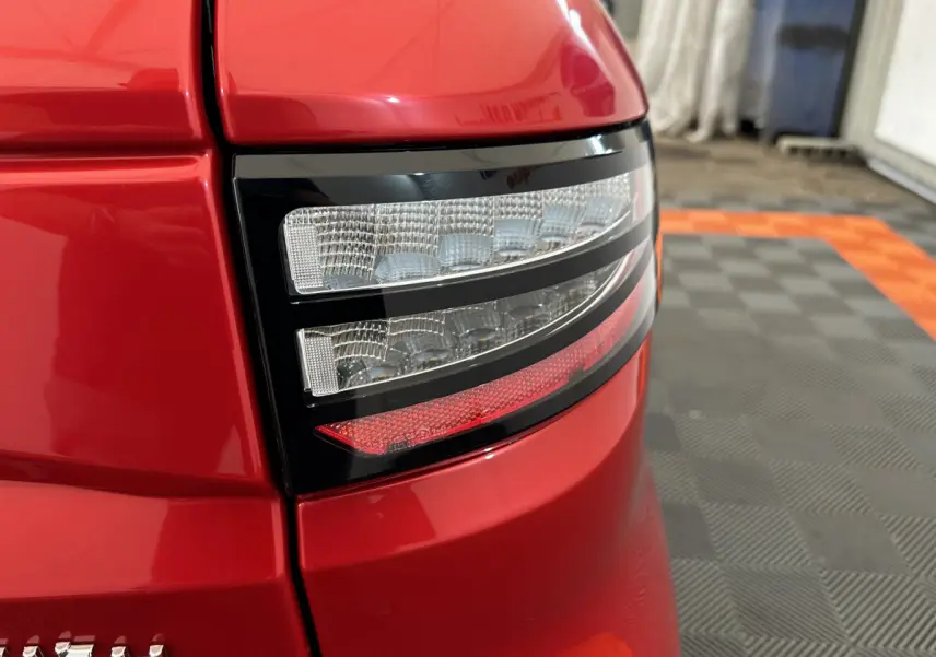Gros plan sur le feu arrière droit rouge brillant de l'AIXAM AMBITION E CITY PACK 2025 avec détails LED et carrosserie lisse.