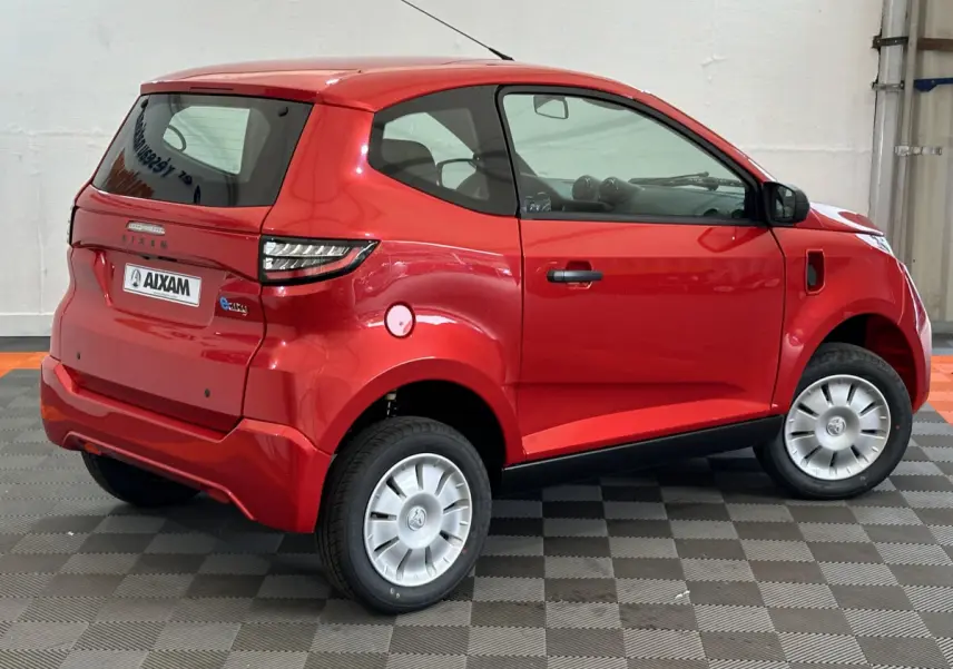 Vue 3/4 arrière droite d'une Aixam Ambition E City Pack rouge 2025 avec caméra sur rétroviseur côté conducteur.