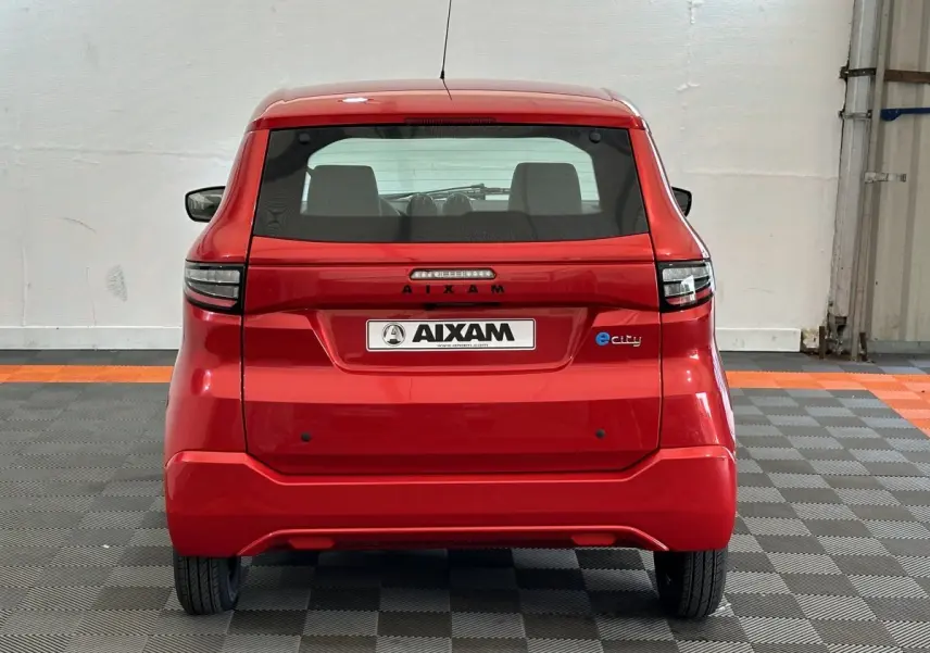 Vue arrière d'une AIXAM AMBITION E CITY PACK rouge électrique 2025 avec logo e-city sur le hayon.