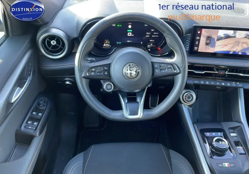 Vue intérieure frontale de l'Alfa Romeo Tonale blanc, volant cuir sport et écran tactile avec caméra de recul.