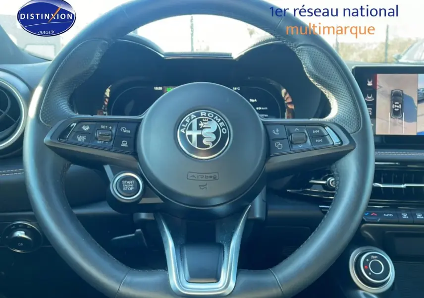 Vue intérieure centrée sur le volant cuir noir de l'Alfa Romeo Tonale 2025 avec tableau de bord digital et écran tactile.