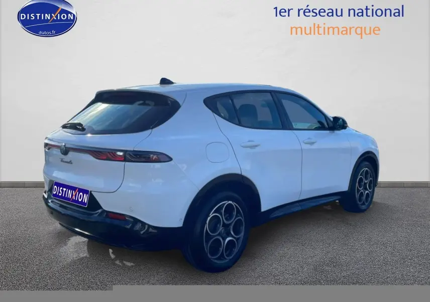 Vue 3/4 arrière droite d'un Alfa Romeo Tonale blanc avec jantes alu distinctives et feux arrière LED fins.