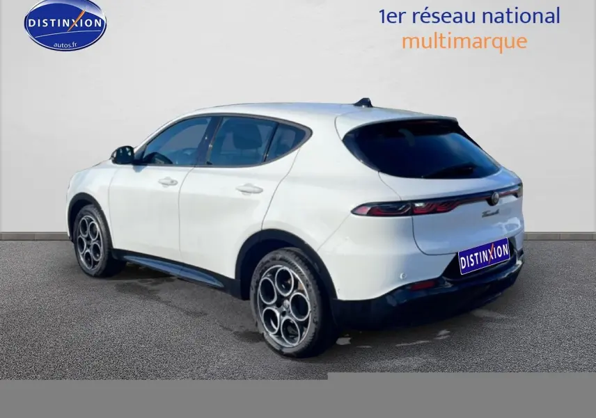 Vue 3/4 arrière droite d'une Alfa Romeo Tonale blanche avec jantes alu et feux arrière LED allumés.