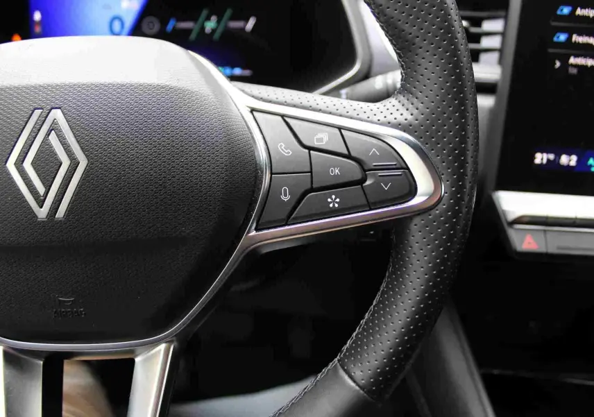 Gros plan sur le volant en cuir perforé de la Renault Symbioz 2025, avec commandes multifonctions visibles à droite.