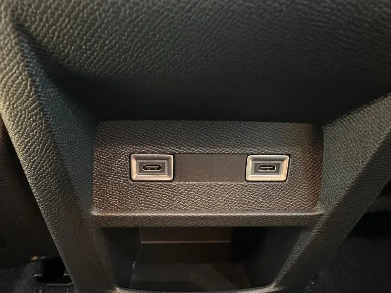 Gros plan sur deux prises USB-C intégrées dans la console arrière noire d'une Peugeot 308 Rouge Elixir.