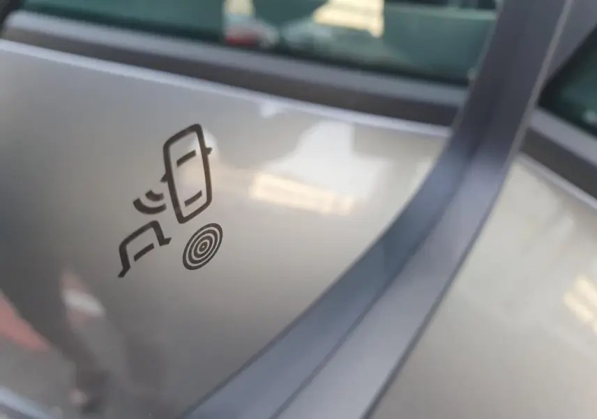 Détail du logo d’alerte de détection d’angle mort sur la vitre côté droit d’un Dacia Bigster gris schiste.