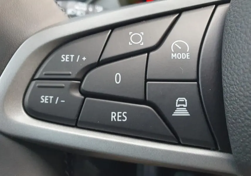 Gros plan sur les commandes noires du volant du Dacia Bigster 2026, boutons de régulateur et mode de conduite.