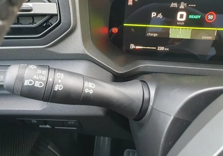 Gros plan sur le commodo des feux et tableau de bord numérique du Dacia Bigster 2026, intérieur noir.