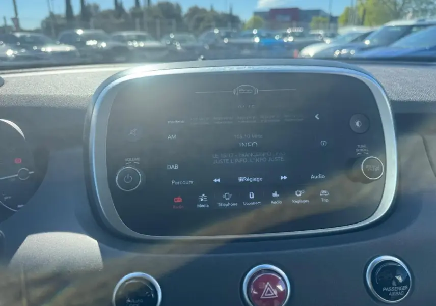Vue rapprochée de l’écran tactile central du tableau de bord du Fiat 500X bleu, affichant les options multimédia.