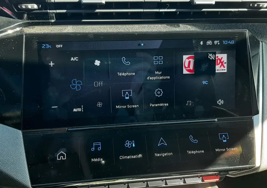 Vue rapprochée de l’écran tactile central du tableau de bord de la Peugeot 308 SW Hybrid 2025, affichant les commandes multimédia et climatisation.