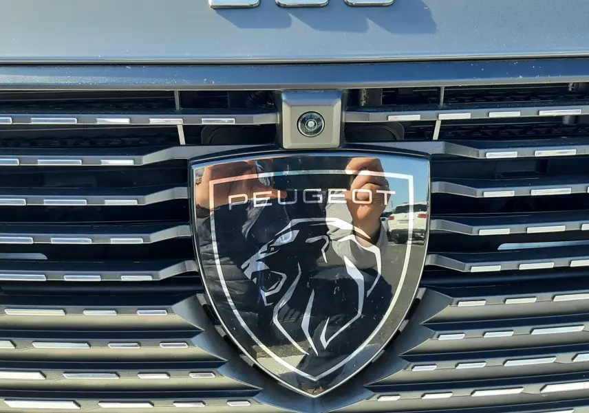 Gros plan sur la calandre gris selenium metal de la Peugeot 308 SW Hybrid avec logo lion et badge 308 en relief.