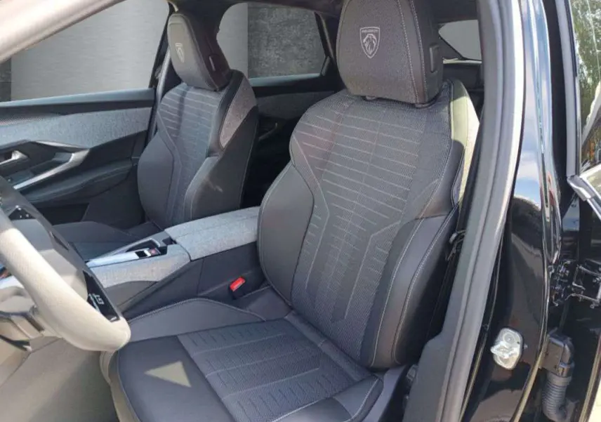 Vue intérieure côté conducteur du Peugeot 3008 New Hybrid 145 GT 360 noir perla nera, sièges avant avec logo Peugeot brodé.