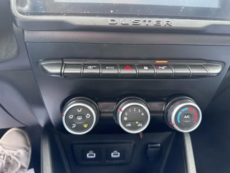 Vue rapprochée du tableau de bord du Dacia Duster 2022 bleu métal, montrant les commandes de climatisation et les boutons de fonction.