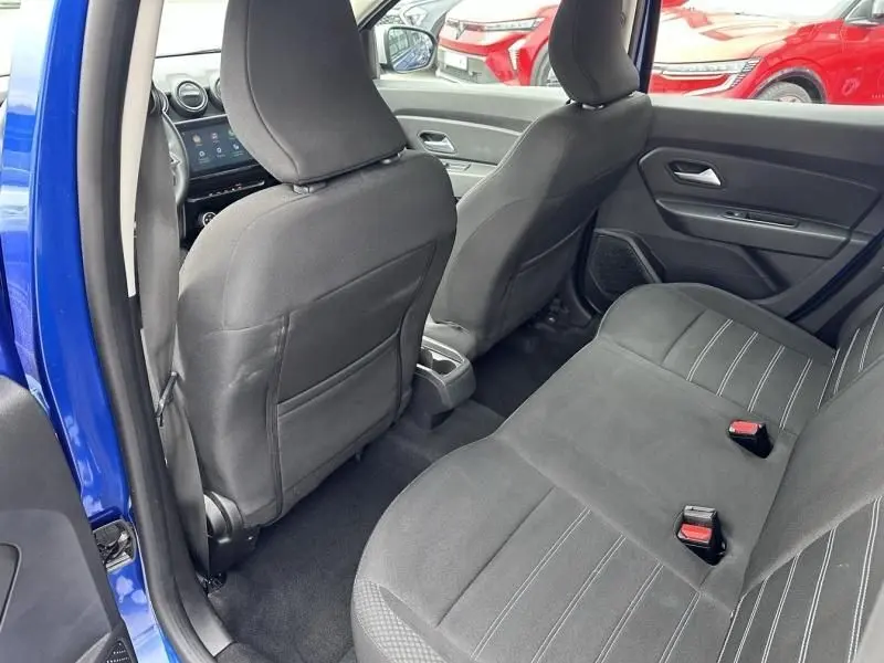 Vue intérieure arrière côté gauche du Dacia Duster bleu métal 2022, montrant les sièges arrière et l'avant du véhicule.