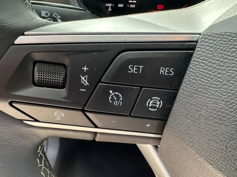 Gros plan sur les commandes multifonctions noires du volant cuir du SEAT Arona 2025, côté gauche.