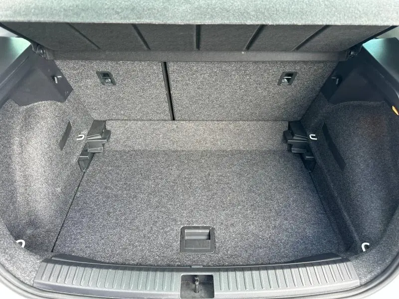 Coffre ouvert vu de dessus du SEAT Arona 2025, intérieur gris avec tapis de sol et banquette arrière rabattable.