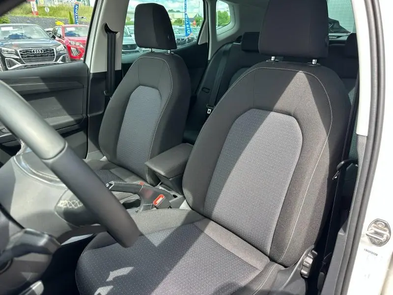 Vue intérieure côté conducteur du SEAT Arona 2025, sièges tissu gris Como avec accoudoir central noir.