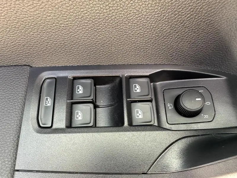 Gros plan sur les commandes de lève-vitres et réglage des rétroviseurs côté conducteur du SEAT Arona blanc.