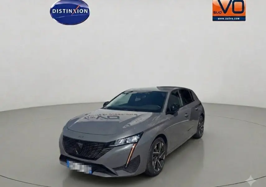 Peugeot 308 gris vue 3/4 avant droit, avec jantes alliage 17 pouces et feux LED distinctifs verticaux.