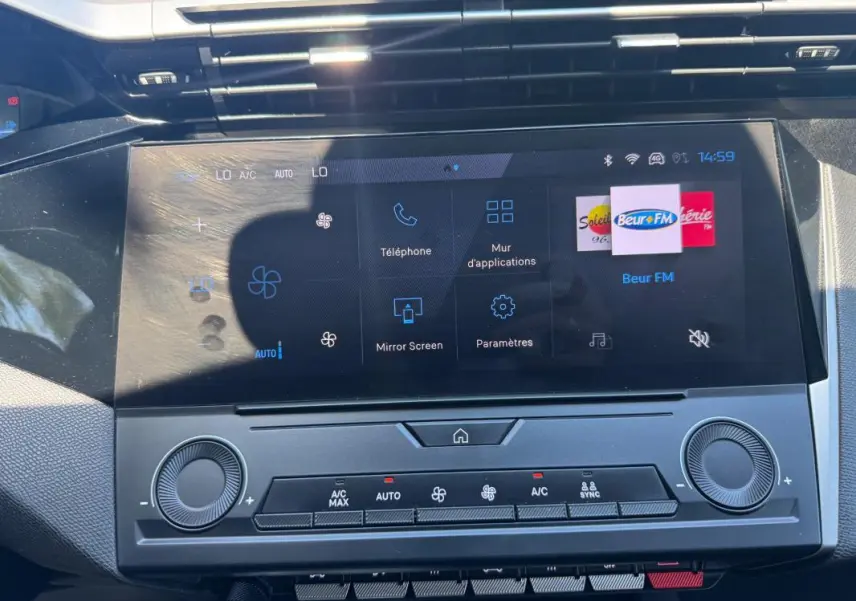Vue rapprochée du tableau de bord de la Peugeot 308 gris 2025, avec écran tactile multifonction et commandes climatisation.