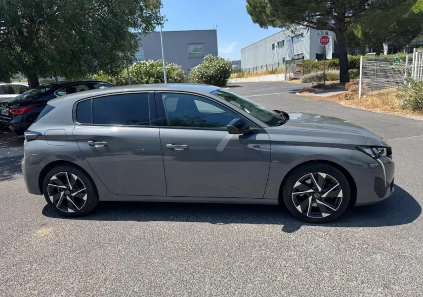 Peugeot 308 gris vue de profil côté gauche, avec jantes alliage 17 pouces et vitres teintées.