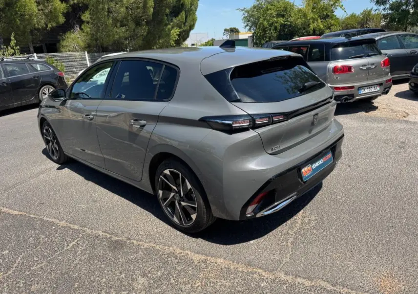 Vue 3/4 arrière droite d'une Peugeot 308 gris métallisé 2025 avec jantes alliage 17 pouces et feux arrière LED distinctifs.