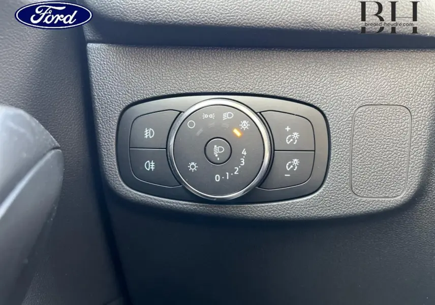 Gros plan sur le bouton de réglage des phares dans l’habitacle noir d’une Ford Focus Titanium X 2022.