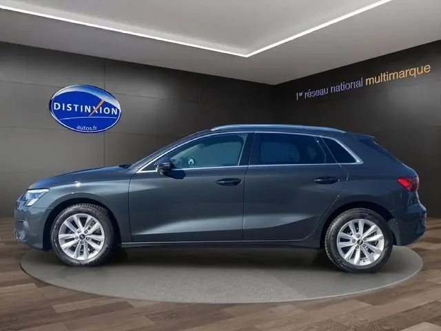 Vue latérale droite d'une Audi A3 Sportback gris Manhattan avec vitres arrière surteintées dans un showroom.