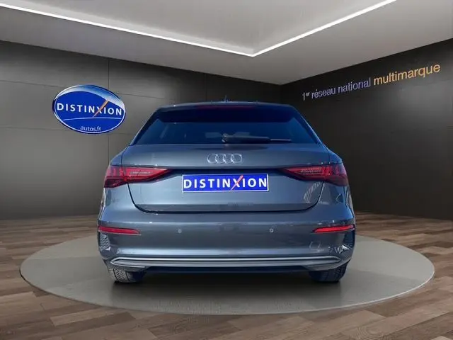 Vue arrière d'une Audi A3 Sportback gris Manhattan avec vitres arrière surteintées dans un showroom.