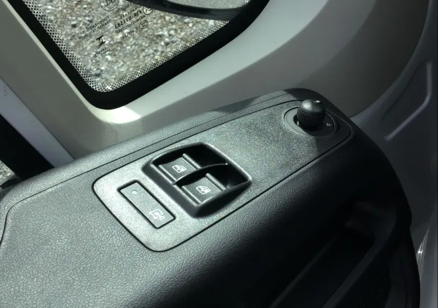 Gros plan sur les commandes de lève-vitres et rétroviseurs côté conducteur du Peugeot Boxer Fourgon blanc 2025.