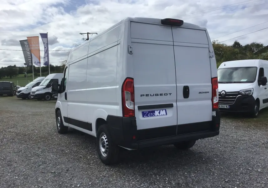Vue 3/4 arrière droite d’un Peugeot Boxer blanc 2025 avec portes arrière fermées et logo Zero KM sur un parking extérieur.