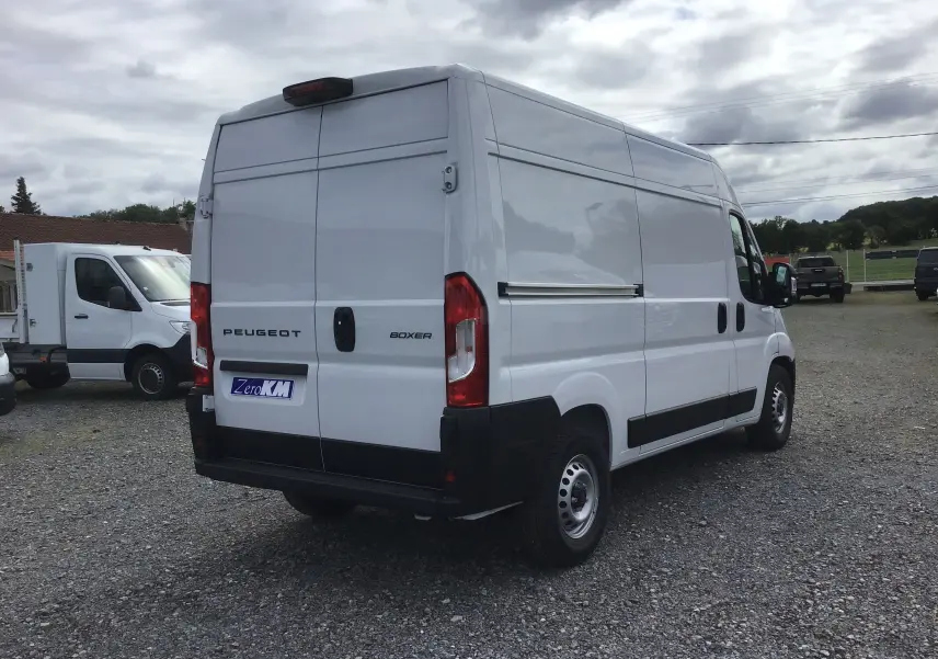 Vue 3/4 arrière droite d'un Peugeot Boxer Fourgon blanc 2025 avec hayon arrière et marquages visibles sur porte.
