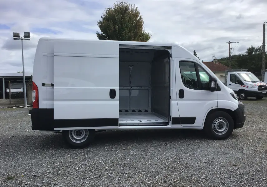 Vue latérale droite d'un Peugeot Boxer blanc 2025 avec porte coulissante ouverte montrant l'espace de chargement vide.