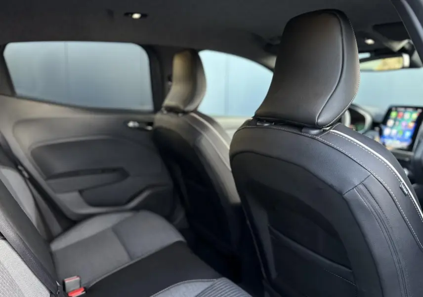 Vue intérieure arrière de la Renault Clio 2025 gris schiste, sièges tissu et cuir noir avec surpiqûres blanches visibles.