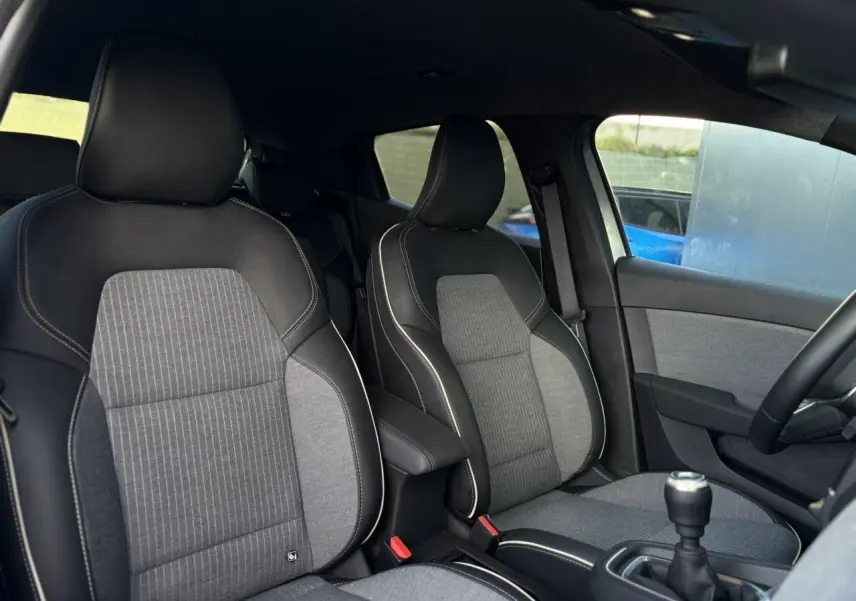Vue intérieure des sièges avant en tissu gris et noir de la Renault Clio V TCE 90 Techno avec boîte manuelle.