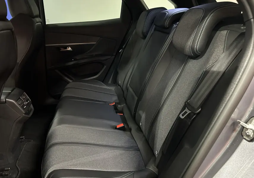 Vue latérale intérieure sur les sièges arrière en tissu et cuir noir du Peugeot 3008 gris Artense, porte arrière ouverte.